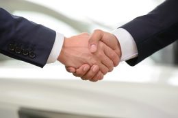 Close-up shoot of the hands shaking in front of the car.